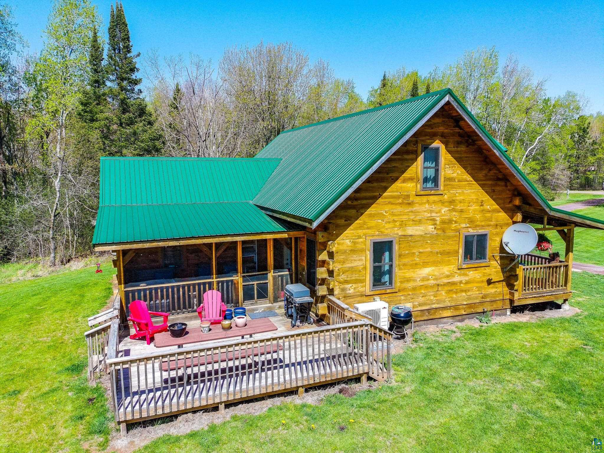 37590 Degerstrom Road Askov, MN 55704 - Photo 3 of 53 Log cabin exterior featuring a green metal roof, a spacious wooden deck with railings, and a screened-in porch