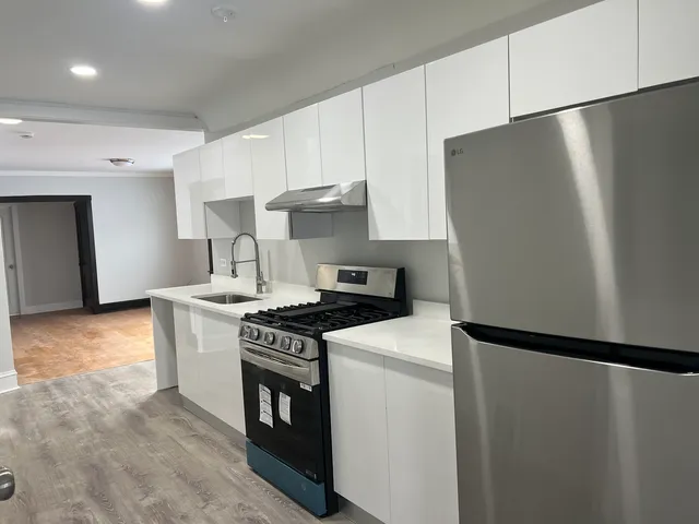 a kitchen with stainless steel appliances a refrigerator a stove and white cabinets