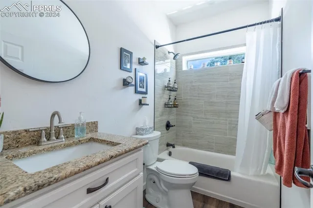 a bathroom with a granite countertop sink toilet and shower