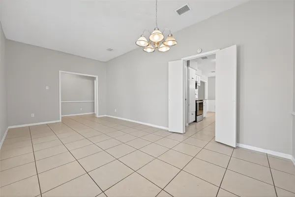 a view of an empty room with a chandelier fan