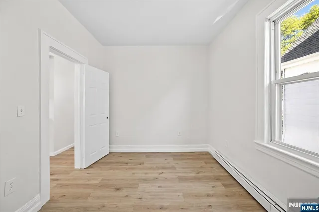 a view of an empty room with wooden floor and windows