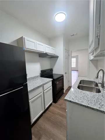 a kitchen with granite countertop a sink stove and refrigerator