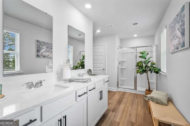 a bathroom with a double vanity sink a potted plant and a window