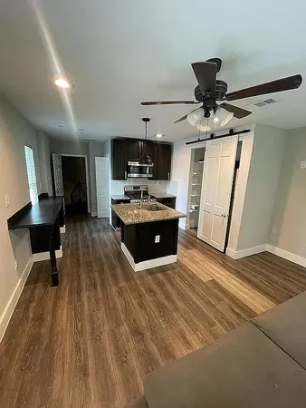 a living room with stainless steel appliances kitchen island granite countertop furniture a rug kitchen view and a wooden floor