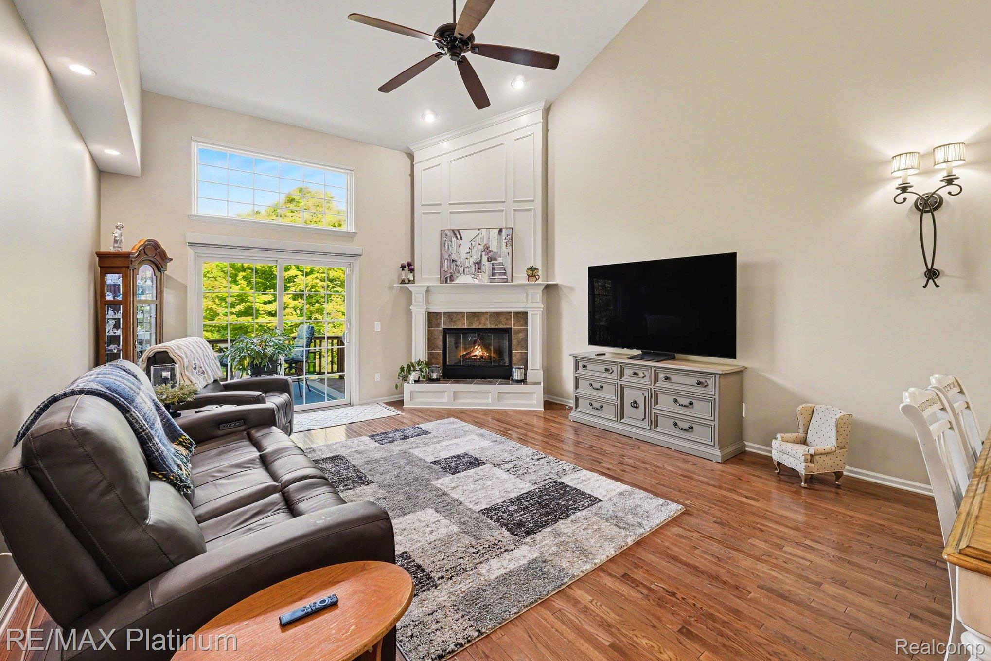 609 Telya Ridge Milford, MI 48381 - Photo 8 of 28 Vaulted ceiling living area featuring hardwood flooring, a gas fireplace with a tiled surround and decorative mantel, and built-in wall paneling