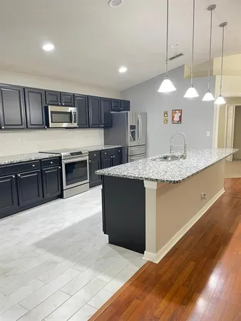 a kitchen with stainless steel appliances granite countertop a sink a stove top oven a counter space and cabinets