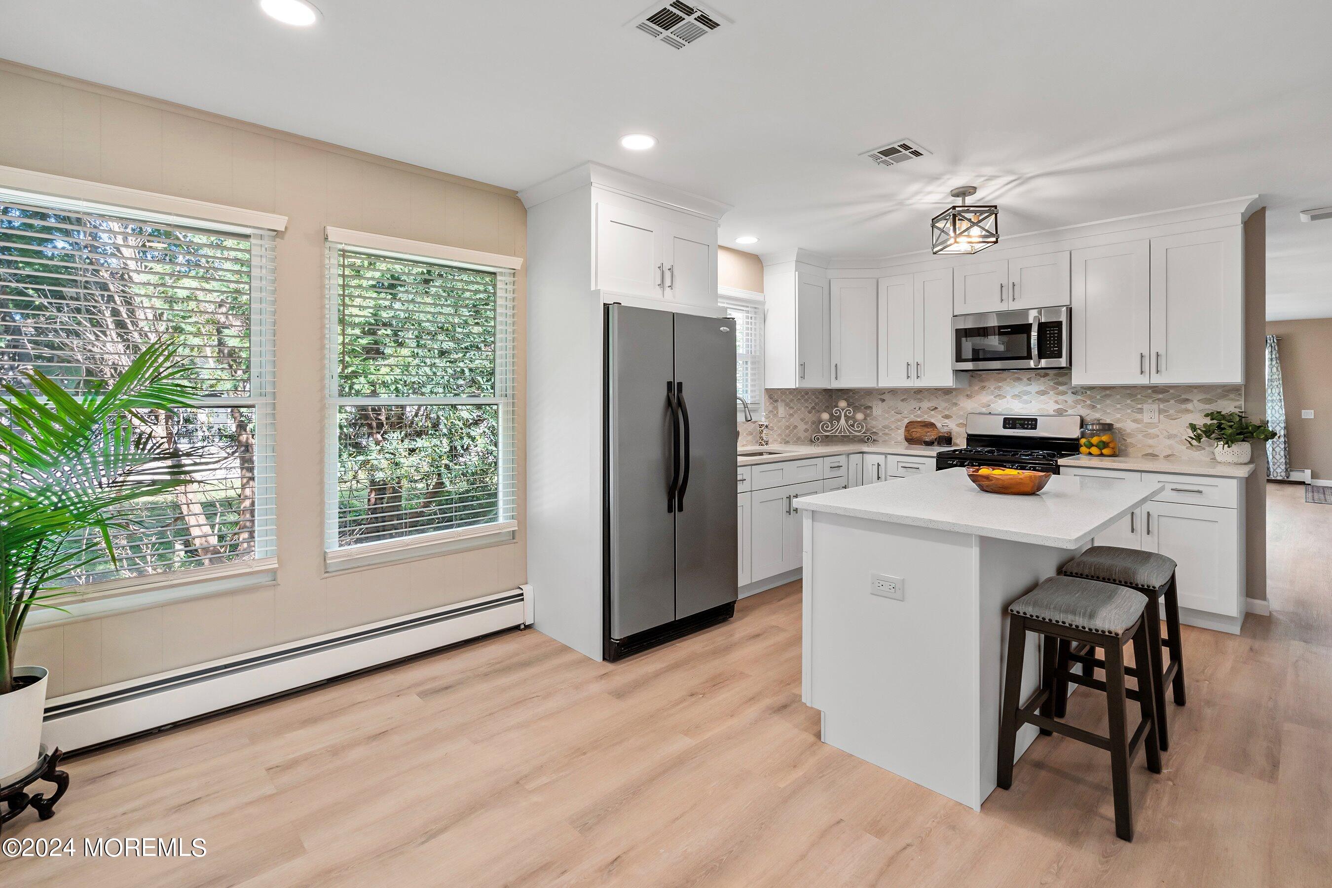 21 Tapola Road Toms River, NJ 08757 - Photo 12 of 22 a kitchen with a refrigerator a microwave oven a sink dishwasher and a dining table with wooden floor