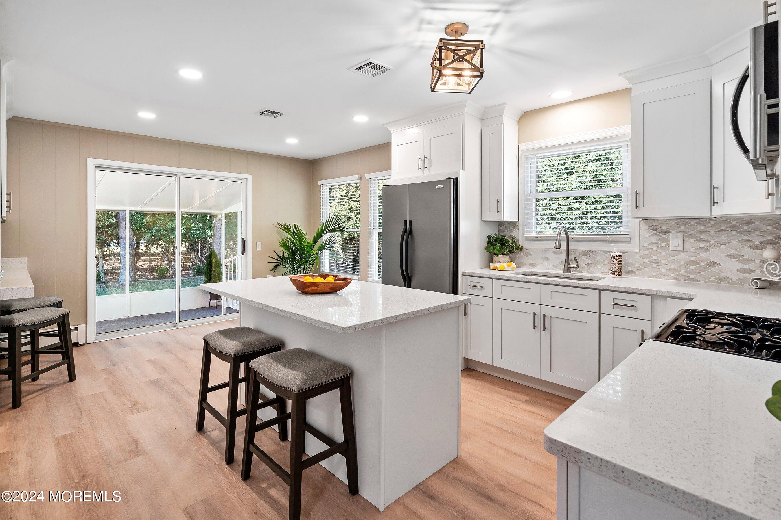 21 Tapola Road Toms River, NJ 08757 - Photo 7 of 22 a kitchen with stainless steel appliances granite countertop a stove a sink a refrigerator and a dining table with wooden floor