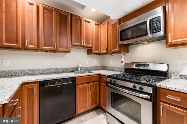 a kitchen with kitchen island granite countertop wooden floors stainless steel appliances a sink and a counter space