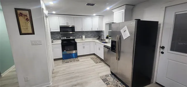 a kitchen with stainless steel appliances granite countertop a refrigerator and a stove top oven