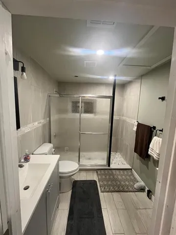 a bathroom with a sink a toilet a mirror and shower