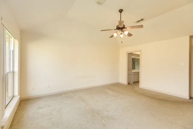 an empty room with a window and a fan