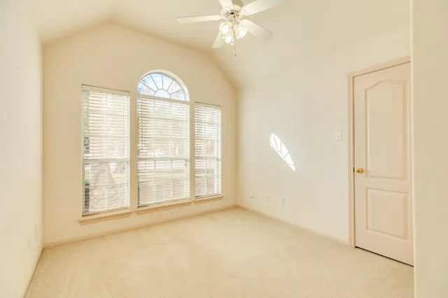 an empty room with windows and ceiling fan