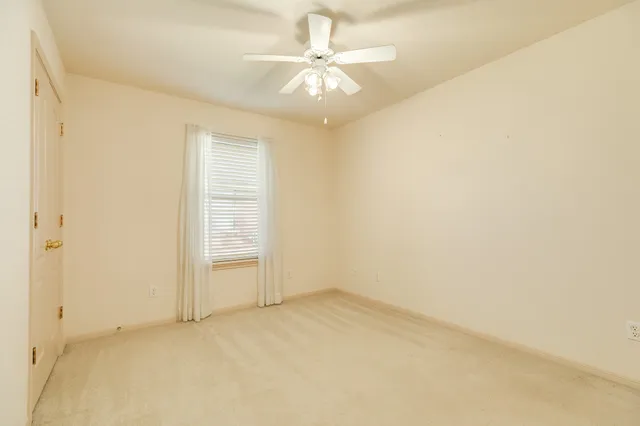 an empty room with a chandelier fan and windows
