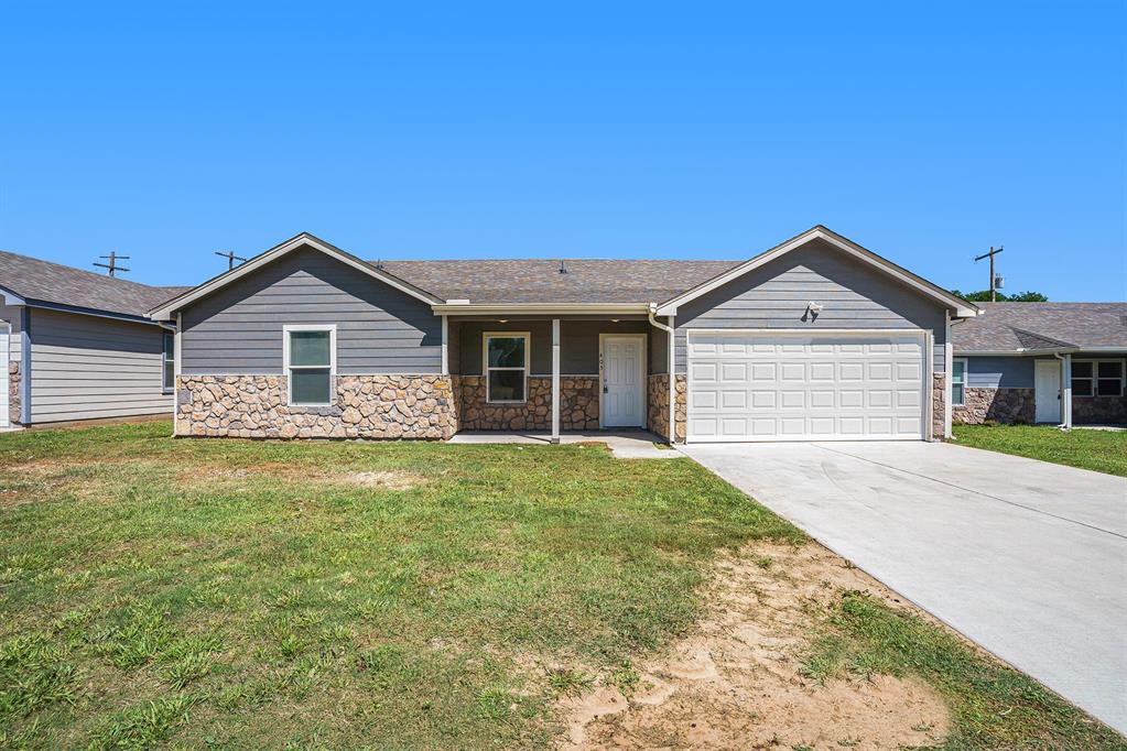 405 North Cleburne Whitney Road Rio Vista, TX 76093 - Photo 1 of 23 Single-story residence featuring a partial stone facade, gray siding, a covered front entry, an attached garage, and a concrete driveway