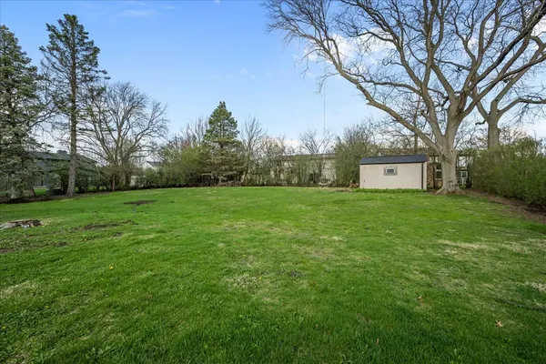 a view of a white house with a big yard and large trees