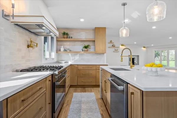 a kitchen with stainless steel appliances granite countertop a sink a stove and a wooden floors