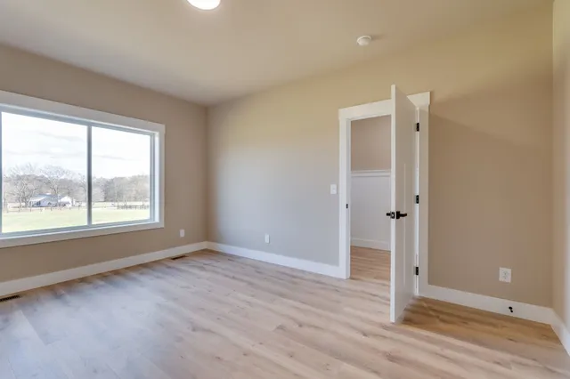 an empty room with wooden floor and window