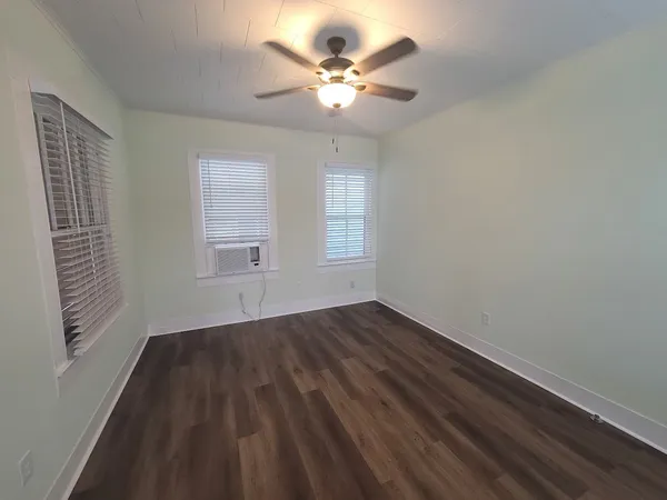 an empty room with wooden floor and windows