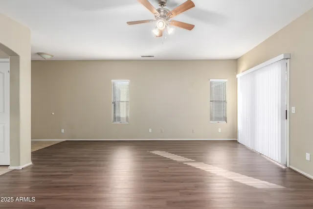 an empty room with wooden floor and windows with curtains