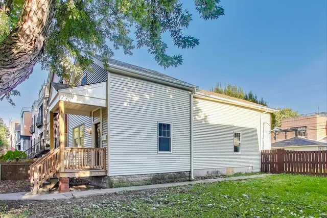 a view of a house with a small yard and wooden fence