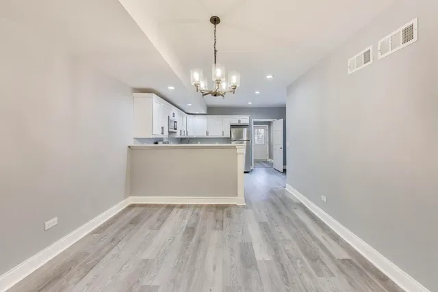 a view of a room with wooden floor and kitchen view