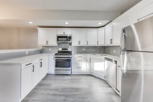 a kitchen with white cabinets and stainless steel appliances