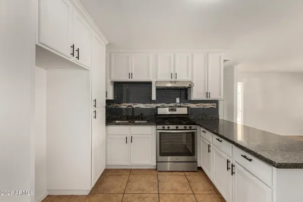 a kitchen with granite countertop a stove and a sink