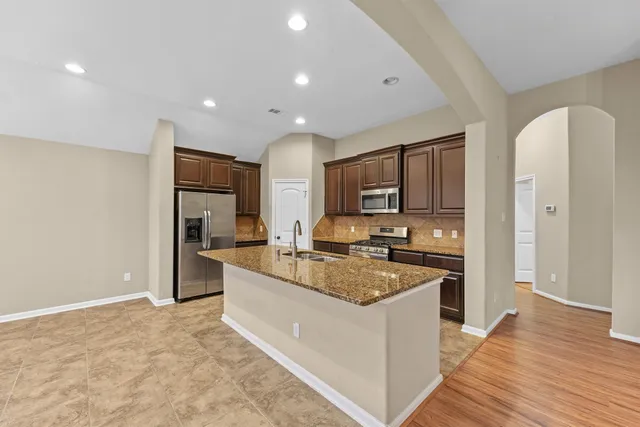 a large kitchen with stainless steel appliances granite countertop a stove top oven a refrigerator a sink and a oven