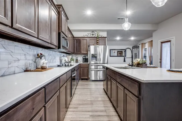a living room with stainless steel appliances kitchen island granite countertop wooden floors and a view of living room