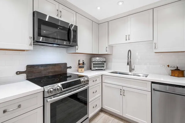 a kitchen with cabinets stainless steel appliances a sink and a counter space