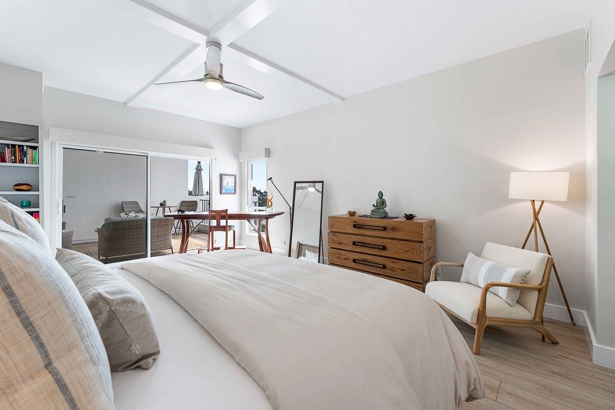 75-6040 Alii Drive, Unit 704 Kailua-Kona, HI 96740 - Photo 18 of 30 a bedroom with a bed and a chair with the wooden floor