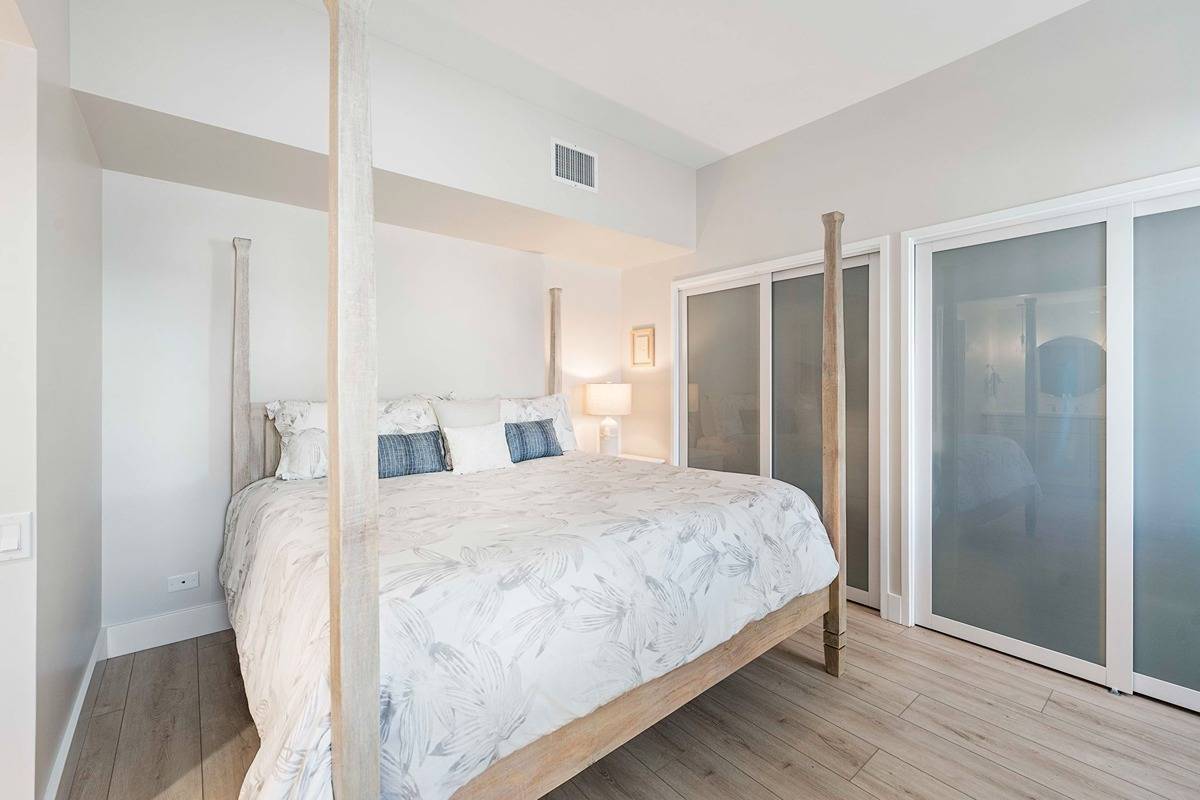 75-6040 Alii Drive, Unit 704 Kailua-Kona, HI 96740 - Photo 23 of 30 a bedroom with a bed and wooden floor