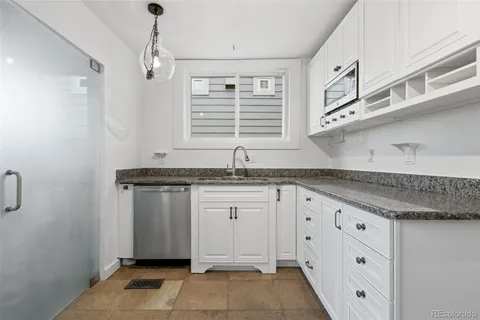 a kitchen with granite countertop white cabinets and window