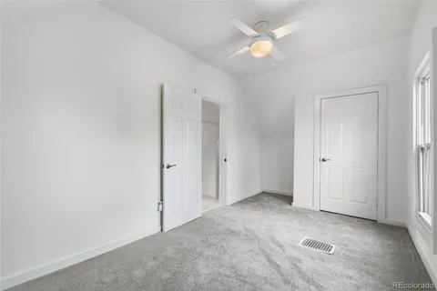 an empty room with closet and a ceiling fan