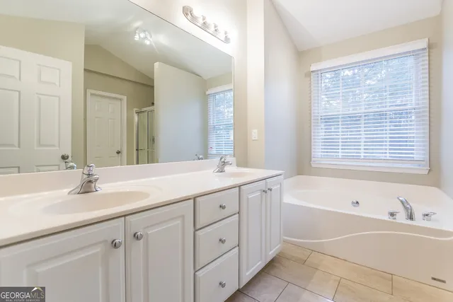 a bathroom with a tub sink double vanity granite and a mirror