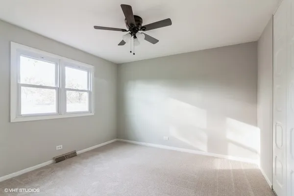 an empty room with a window and a fan
