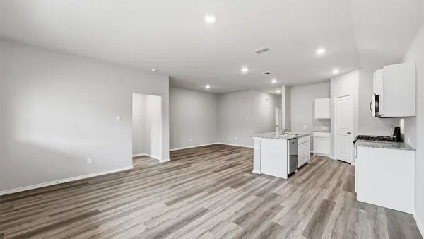 a view of an empty room with wooden floor and windows
