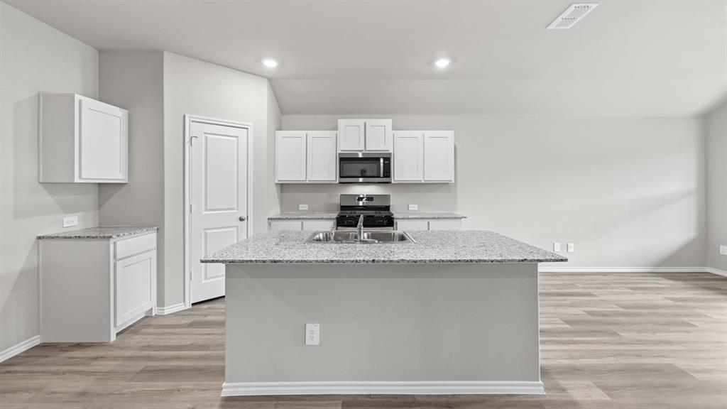 a kitchen with kitchen island granite countertop a sink stove and refrigerator