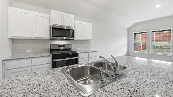 a kitchen with granite countertop a sink stove and refrigerator