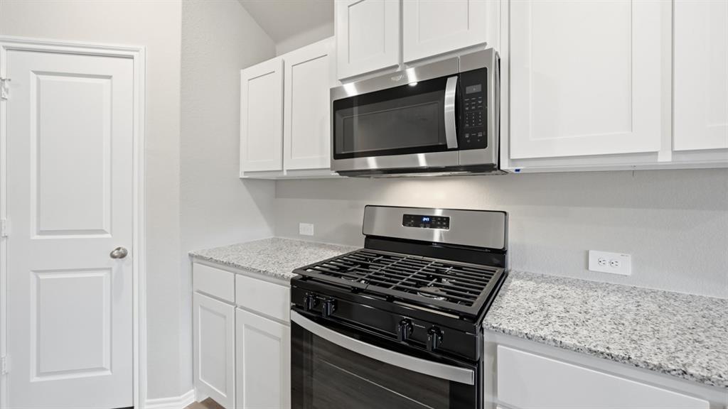 1632 Tin Roof Road Krum, TX 76249 - Photo 3 of 34 a kitchen with stainless steel appliances granite countertop white cabinets and a stove top oven