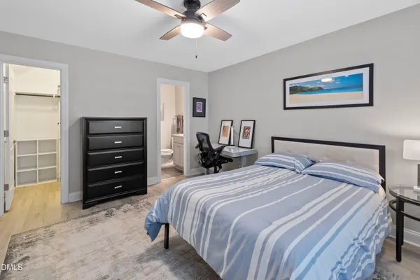 a bedroom with a bed a computer on desk and a dresser next to a window