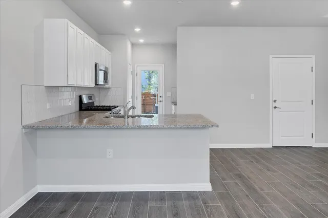 a kitchen with granite countertop kitchen island stainless steel appliances a sink stove and cabinets
