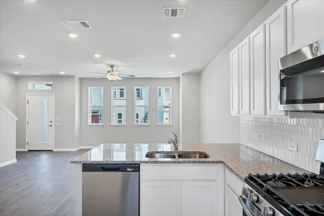 a kitchen with stainless steel appliances granite countertop a stove a sink and a microwave
