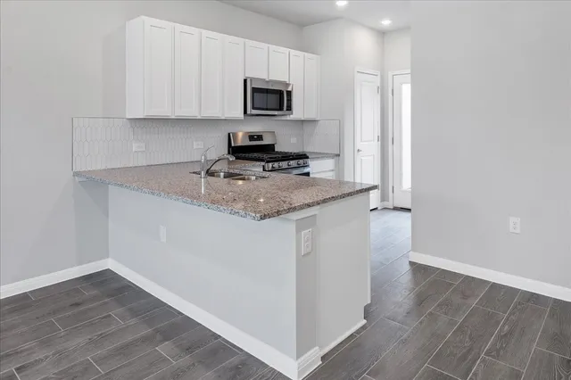 a kitchen with granite countertop white cabinets stainless steel appliances and sink