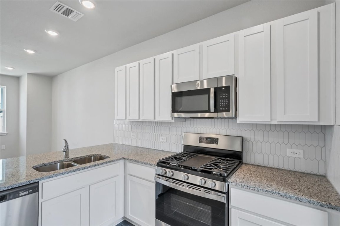 9015 Cattle Baron Path, Unit 1303 Austin, TX 78747 - Photo 9 of 29 a kitchen with granite countertop white cabinets stainless steel appliances and sink