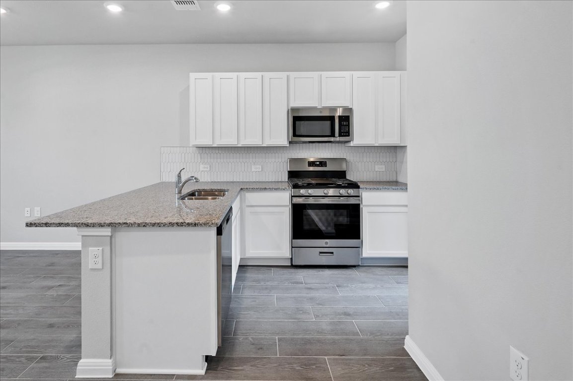 9015 Cattle Baron Path, Unit 1303 Austin, TX 78747 - Photo 10 of 29 a kitchen with stainless steel appliances a stove microwave and sink