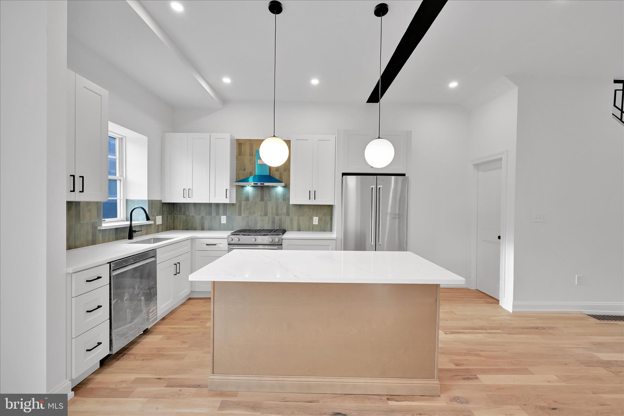 64 East Spring Avenue Ardmore, PA 19003 - Photo 9 of 26 a large kitchen with stainless steel appliances a large counter top a stove a sink dishwasher and a refrigerator with wooden floor