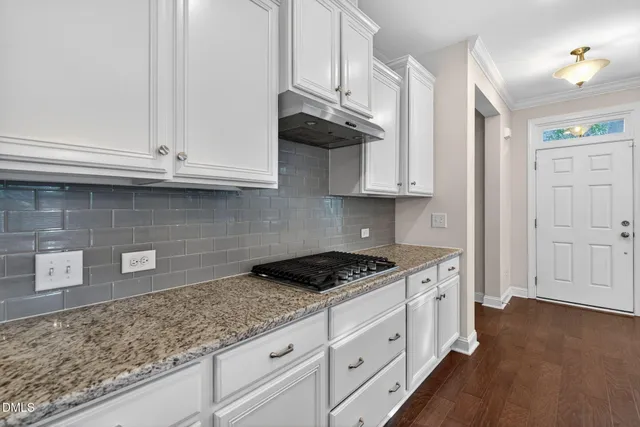 a kitchen with granite countertop white cabinets and a stove