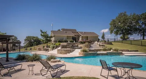 a view of a swimming pool with lawn chairs potted plants and palm tree